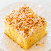 A slice of coconut-topped cake on a white plate.