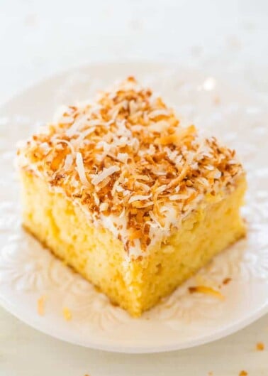 A slice of coconut-topped cake on a white plate.