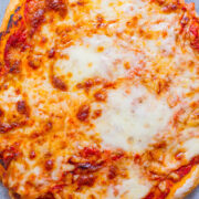 A freshly baked cheese pizza on a gray surface.