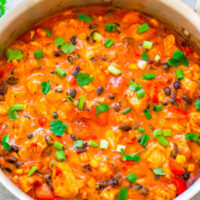 A pot of simmering chicken and vegetable stew garnished with fresh herbs.