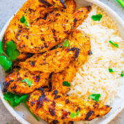 Grilled chicken with herbs served alongside white rice in a bowl.