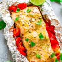 Grilled salmon fillet with red peppers and lime on foil.
