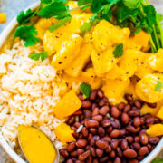 A colorful bowl of rice, beans, and curry with a garnish of fresh herbs.