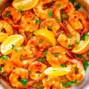 Pan of sautéed shrimp garnished with lemon slices and parsley.