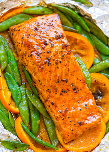 Grilled salmon fillet with snap peas and sliced carrots on aluminum foil.