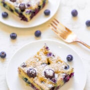 Blueberry pastry dusted with powdered sugar, served on white plates with fresh blueberries.