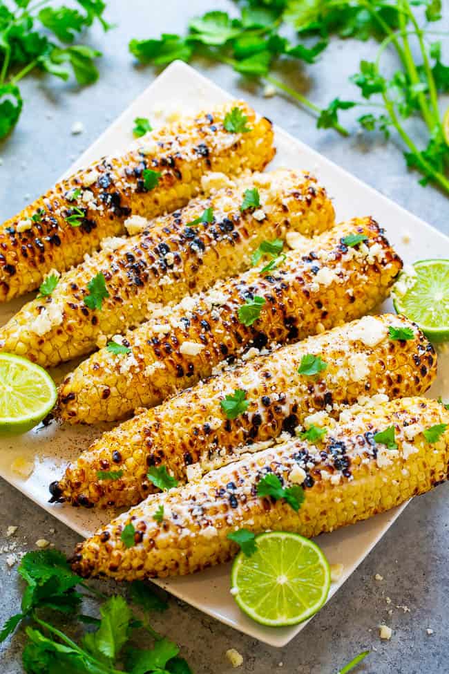 Grilled Mexican Corn (Elote) - Learn how to make this EASY and FLAVORFUL grilled Mexican street corn at home in minutes!! Fresh sweet corn is covered in crema, cheese, and finished with chili, lime juice, and cilantro!!