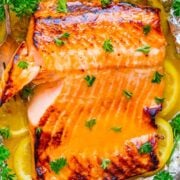 Grilled salmon fillet with lemon and parsley garnish in foil.