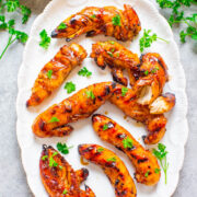 Grilled chicken wings garnished with parsley on a white plate with a side of dipping sauce.