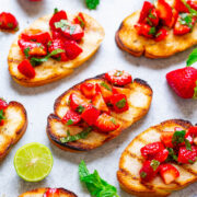 Slices of toasted bread topped with fresh diced strawberries, lime, and mint leaves.