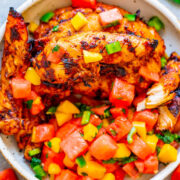 Grilled chicken breast topped with fresh salsa in a bowl.