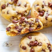 Freshly-baked chocolate chip cookies, one halved to show the soft interior.