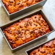 Three loaves of freshly baked banana bread with chocolate chips in loaf pans.