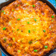 Golden-brown casserole in a blue skillet garnished with green onions.