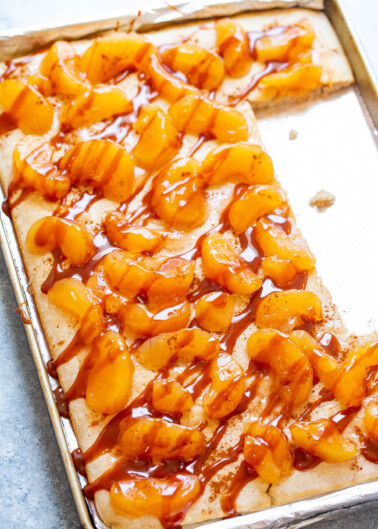 Peach tart with caramel drizzle on a baking sheet.
