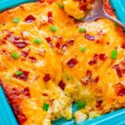 Baked cheesy casserole dish with a serving spoon.