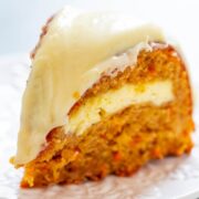 A slice of carrot cake with cream cheese frosting on a white plate.