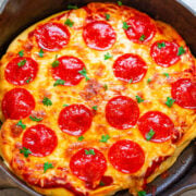 Freshly baked pepperoni pizza in a cast-iron skillet, garnished with parsley.