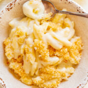 A bowl of creamy macaroni and cheese topped with breadcrumbs.