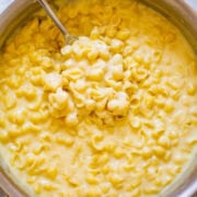 A pot of creamy macaroni and cheese with a spoon inside it.