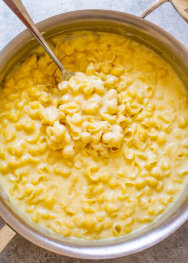 A pot of creamy macaroni and cheese with a spoon inside it.