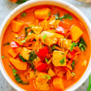 A bowl of colorful chicken and vegetable stew garnished with fresh herbs.