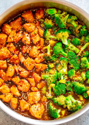 A pot of chicken and broccoli stir-fry garnished with sesame seeds.