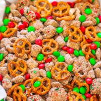 A festive mix of pretzels, candy-coated chocolates, and confectioners' sugar with colorful sprinkles in a decorative bowl.