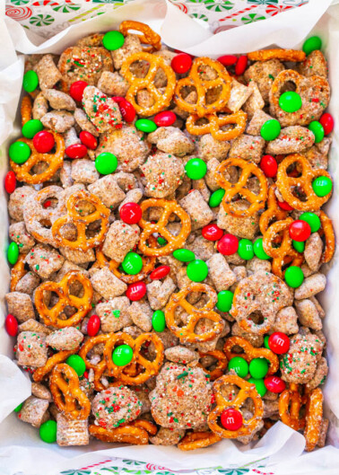 A colorful mix of puppy chow, pretzels, and red and green candies in a festive bowl.