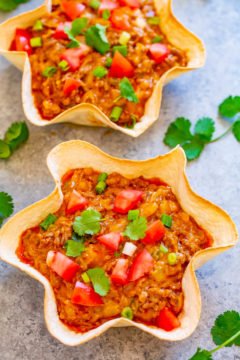 Taco salads served in crispy tortilla bowls, topped with fresh tomatoes and cilantro.