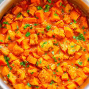 A pot of hearty chicken and potato stew garnished with fresh herbs.
