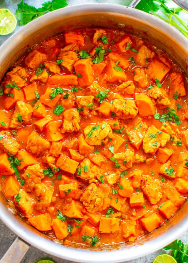 A pot of hearty chicken and potato stew garnished with fresh herbs.