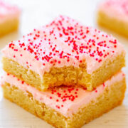 Stack of sugar cookie bars with pink frosting and red sprinkles.