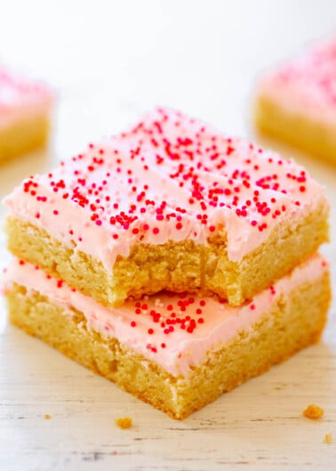 Stack of sugar cookie bars with pink frosting and red sprinkles.