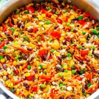 A colorful mixed rice and vegetable dish in a stainless steel pot.