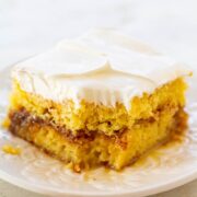 A slice of frosted yellow cake on a plate.