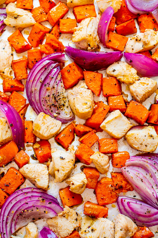 red onion, chicken and sweet potato cubes on a baking tray