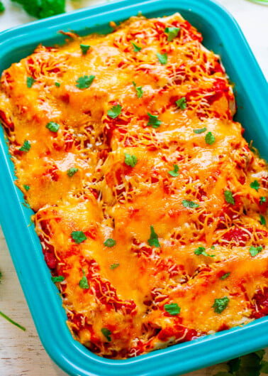 A freshly baked lasagna in a blue dish garnished with chopped parsley.
