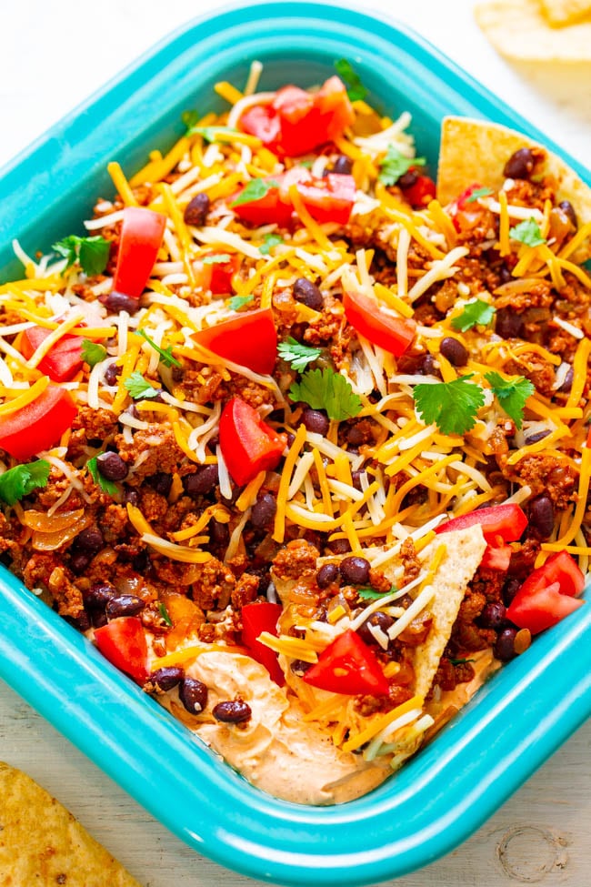 Layered Beef Taco Dip - A FAST and EASY layered dip with taco-seasoned cream cheese, sour cream, ground beef, black beans, cheese, tomatoes, and more!! Perfect for your next FIESTA and a guaranteed WINNER with everyone!!