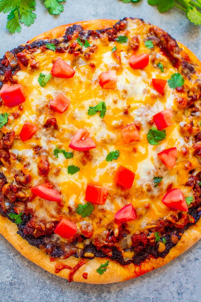 Taco Pizza — EASY, ready in 20 minutes, and like eating a taco in pizza form!! Taco-seasoned ground beef on top of refried beans with melted cheese and your favorite taco fixings!!