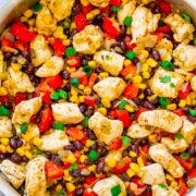 Chicken and vegetable stir-fry with corn, black beans, and red peppers in a skillet.