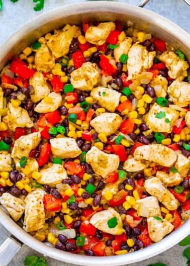 Chicken and vegetable stir-fry with corn, black beans, and red peppers in a skillet.