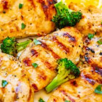 Grilled chicken breasts with broccoli and lemon slices on a plate.