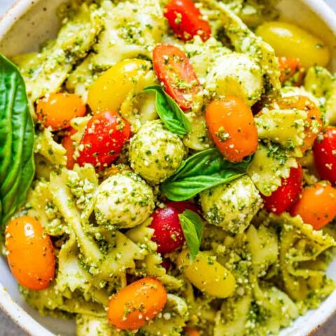 Tomato and Mozzarella Pesto Pasta Salad - Tender pasta, cherry tomatoes, and fresh mozzarella are coated in Parmesan cheese and DELICIOUS pesto sauce!! EASY, ready in 15 minutes, and great for easy meals with planned leftovers or for parties because it feeds a crowd!!