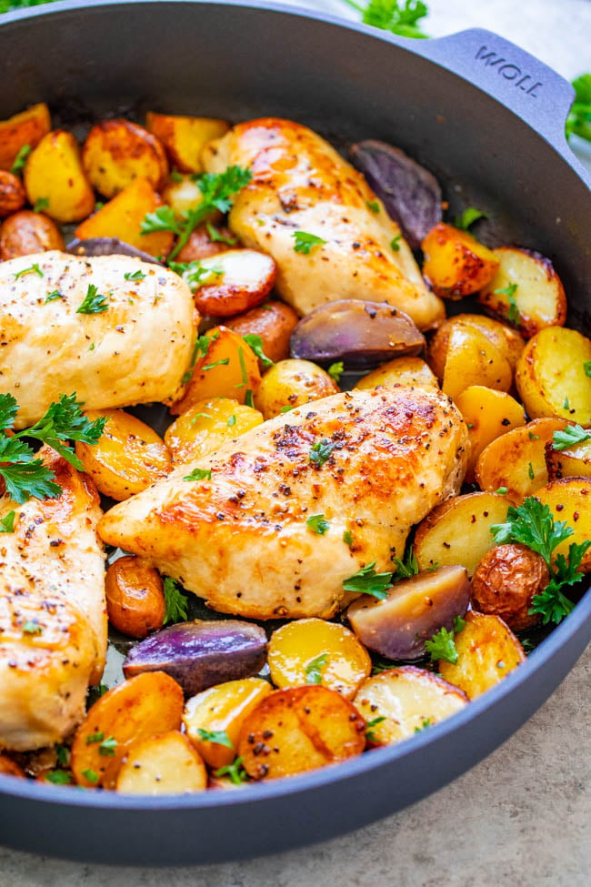 side view of baked chicken breast and potatoes in a skillet 