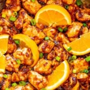 A pot of healthy orange chicken topped with orange slices.