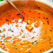 A bowl of Thai chicken coconut curry soup with a spoon sticking out.