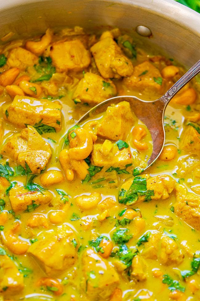 close up of indian yellow curry in a skillet with a spoon 