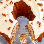 Hummingbird Cake with cream cheese frosting, a slice missing and a fork holding a bite in the empty space.