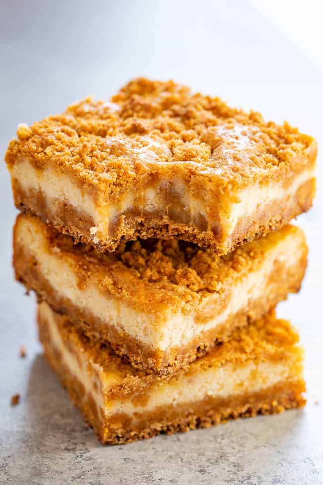 a stack of three butterscotch cheesecake bars. the top bar has a bite missing. 